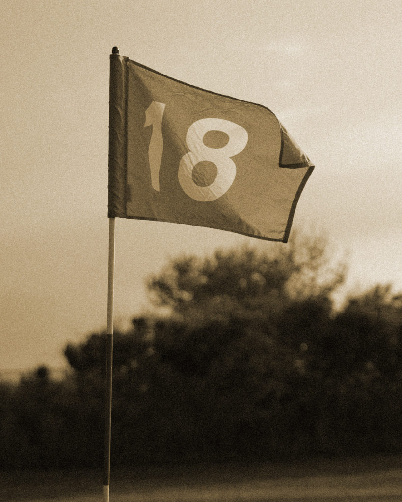 Golf flag proudly waving atop a perfectly manicured green